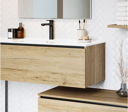 Meuble de salle de bain en bois clair avec un robinet noir, miroirs, et accessoires sur fond de carrelage blanc en chevrons.